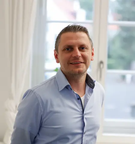 David Raitza lächelnd am Fenster im Büro