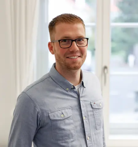 Marvin Adrian lächelnd am Fenster im Büro